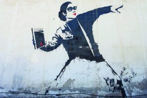 graffiti of a woman holding a book and ready to throw it like a bomb