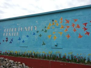 Image of a mural with a blue backgroupd and colored birds and flowers. The words "opportunity center" are painted on the wall.