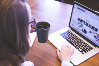 woman drinking tea while working on a computer