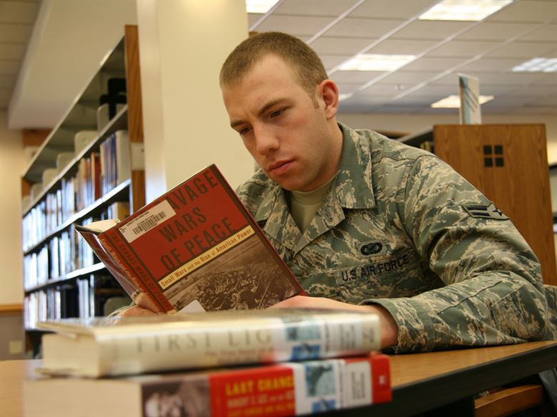 Photograph: a uniformed military person reading in a library