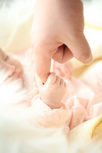 A photo of an infant holding a caregiver's finger