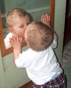 Baby kissing an image of themselves in a mirror