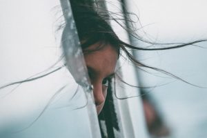 A shy child peeking out a window