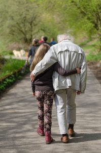 image of a grandchild and grandparent walking arm in arm in a park