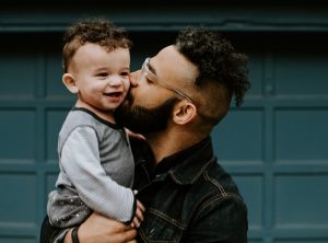 A parent holding their child and giving them a kiss