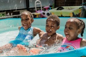 Three children splashing in a pool